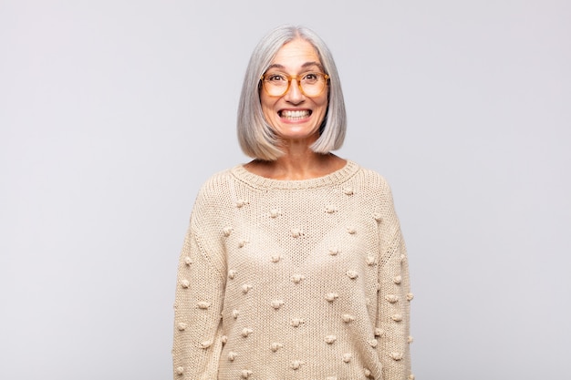 Mulher de cabelos grisalhos, parecendo feliz e boba, com um sorriso largo, divertido e maluco e olhos bem abertos