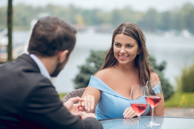 Mulher de cabelos muito compridos feliz olhando com amor e o homem segurando a mão de costas para a câmera