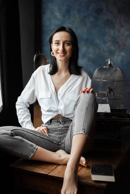 Mulher de camisa branca e jeans em casa