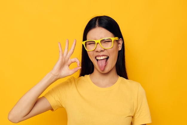 Mulher de camiseta amarela com óculos posando fundo amarelo de moda inalterado