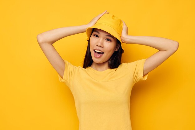 Mulher de camiseta amarela e chapéu posando emoções isoladas de fundo inalterado