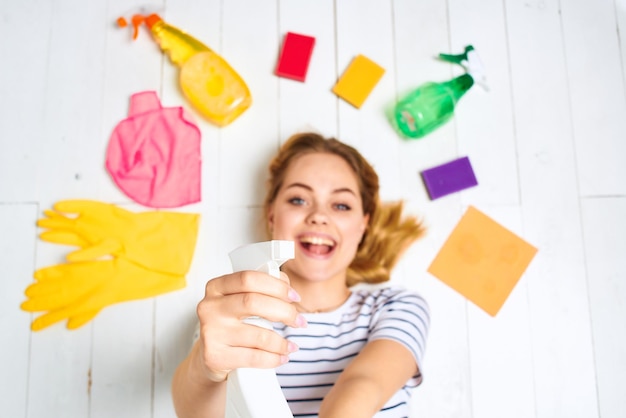 Mulher de camiseta listrada deita no chão material de limpeza detergente trabalho doméstico