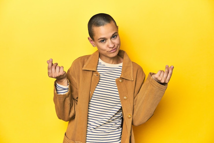 Foto mulher de camisola listrada e camisa jeans com fundo amarelo mostrando que ela não tem dinheiro