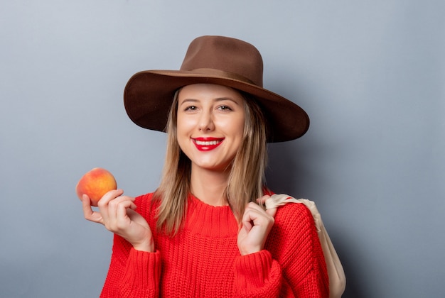 Mulher de camisola vermelha com pêssego e bolsa