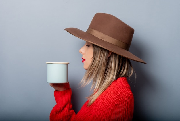 Mulher de camisola vermelha e chapéu com uma xícara de café