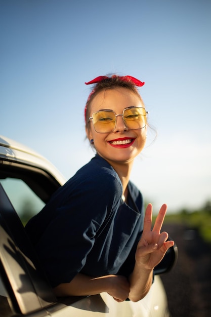 Mulher de carro na estrada em viagem acenando feliz e sorrindo pela janela
