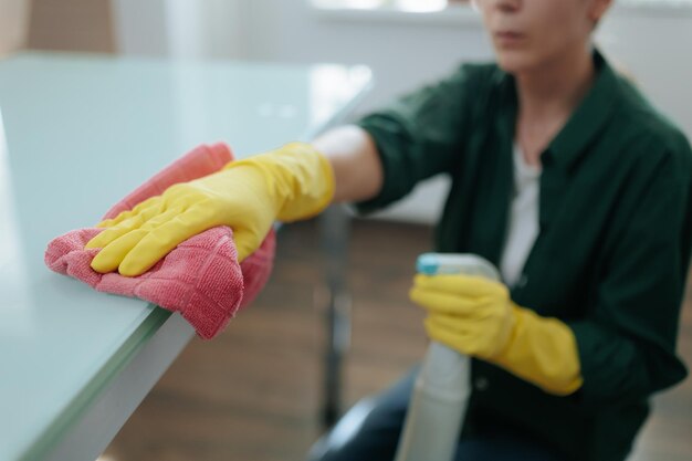 Mulher de casa com luvas de proteção limpando sua cozinha