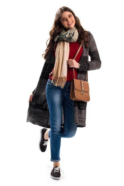 Mulher de casaco. Bolsa marrom e jeans. Roupa de outono com lenço elegante. Novas agasalhos e acessórios.