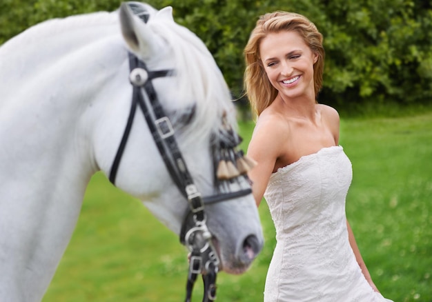 Mulher de casamento e feliz com cavalo ao ar livre na grama para celebração casamento ou confiança no campo Pessoa da noiva e garanhão no gramado no campo com sorriso vestido ou animal em evento na natureza