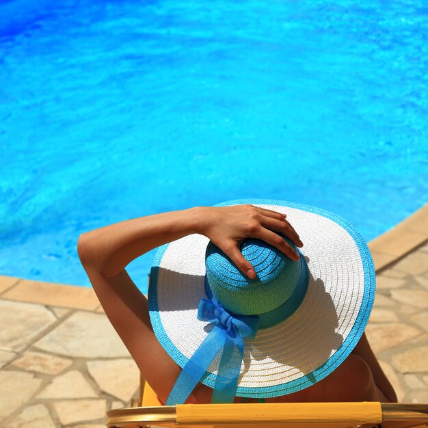 Foto mulher de chapéu à beira da piscina