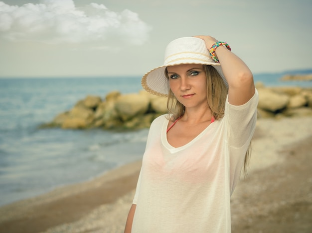Mulher de chapéu com pulseiras coloridas na praia.