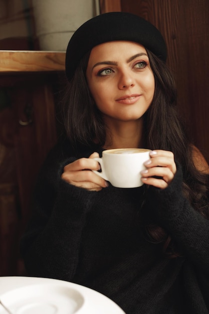 Mulher de chapéu com uma xícara de café