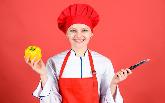 Mulher de chapéu de cozinheiro e avental chef profissional na cozinha Cozinha Dona de casa com faca de cozinha mulher feliz cozinhando comida saudável por receita pimentão Economize seu tempo