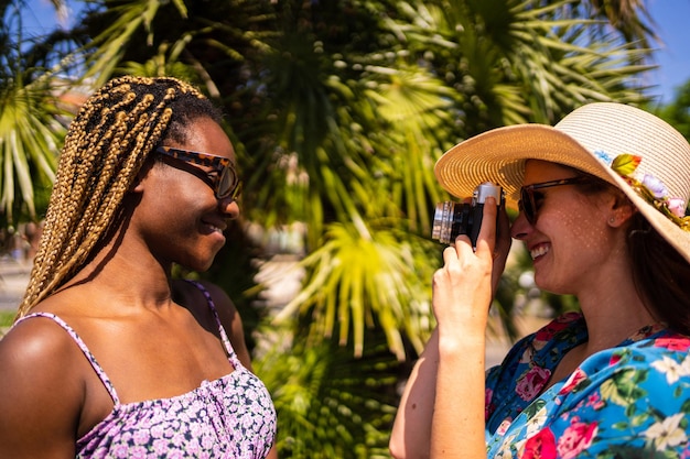 Mulher de chapéu de palha tirando fotos com uma câmera de uma mulher negra