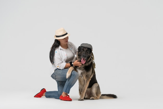 Mulher de chapéu e pastor do leste europeu usando boné posando em fundo branco. conceito de animal de estimação