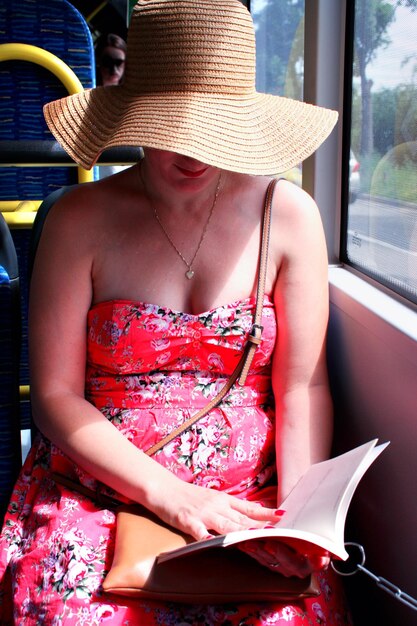 Mulher de chapéu lendo ebook no ônibus de trem