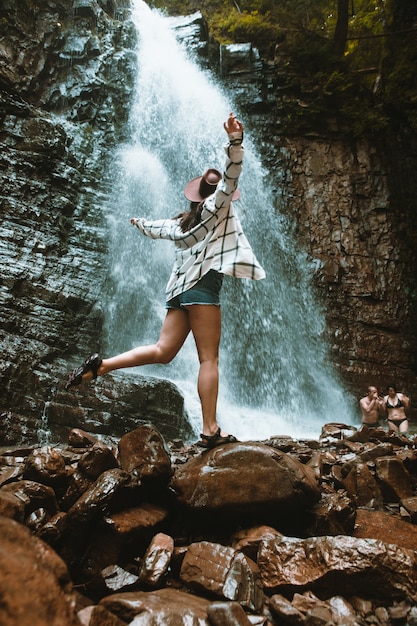 Mulher de chapéu marrom apreciando a vista do conceito de viagem para caminhadas na cachoeira