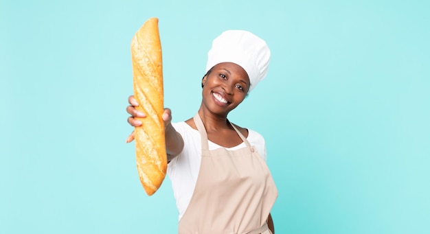 Mulher de chef adulto afro-americano negro segurando uma baguete de pão