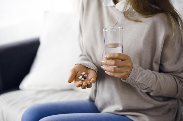 Foto mulher de close-up segurando pílulas na hora de tomar remédios para curar dores de cabeça, pressão alta, medicamentos analgésicos em casa fique em casa conceito durante a pandemia de coronavirus