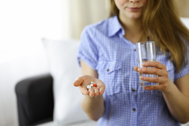 Foto mulher de close-up segurando pílulas tempo para tomar medicamentos, cura para dor de cabeça, pressão arterial alta ou nível de colesterol remédio drogas analgésicas. conceito de medicina.