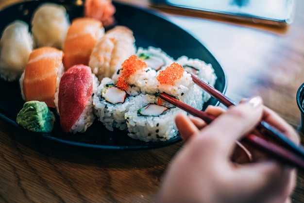 Mulher de colheita comendo sushi