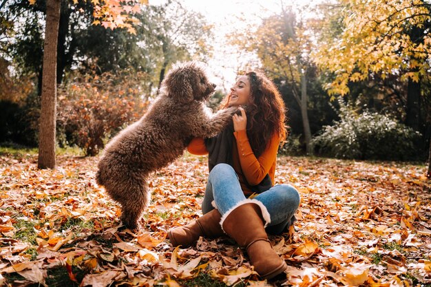 Foto mulher de comprimento completo com cachorro sentado no parque