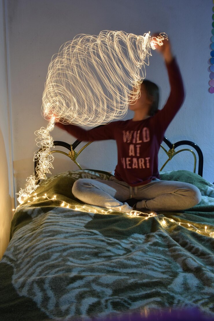Foto mulher de comprimento completo segurando equipamento de iluminação sentada na cama em casa