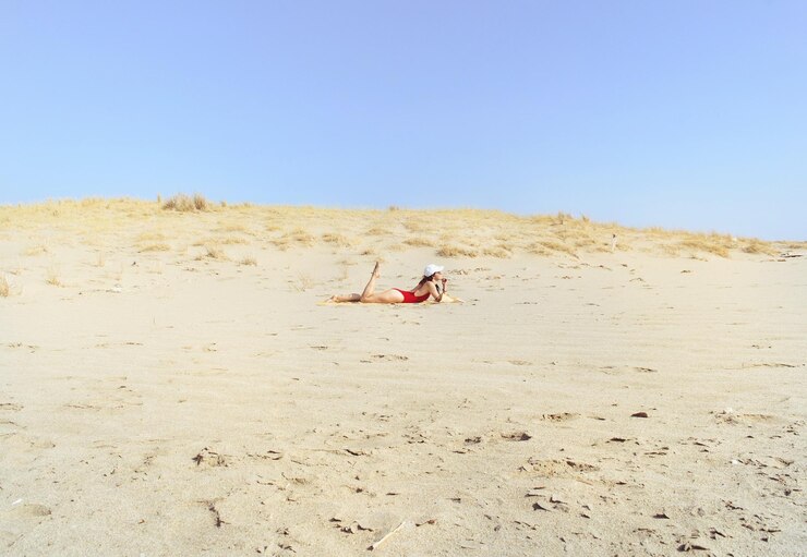 Foto mulher de comprimento completo tomando banho de sol na areia da praia