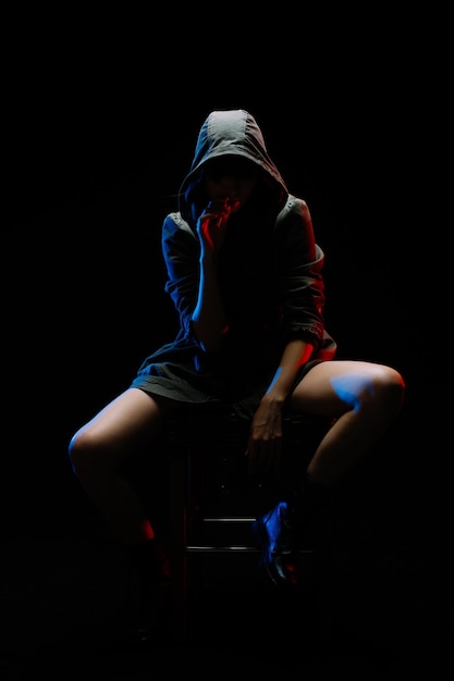 Mulher de comprimento inteiro sentada contra um fundo preto