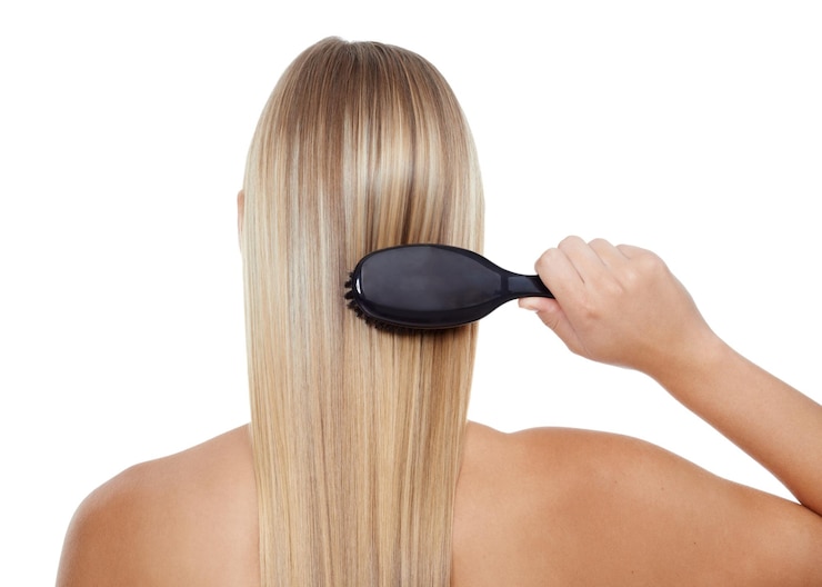 Foto mulher de costas e penteando o cabelo para textura de cuidados ou tratamento de salão em um fundo de estúdio branco vista traseira de modelo de pessoa feminina ou loira com escova para cuidados com o cabelo queratina ou brilho em maquete