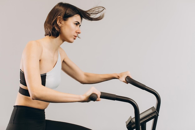 Mulher de crossfit fazendo treinamento cardio intenso na bicicleta de exercício