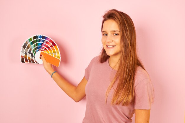 Foto mulher de designer de interiores segurando uma paleta de guia de cores isolada em fundo amarelo