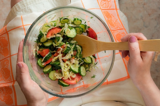 Mulher de dieta com prato de salada crua nos joelhos