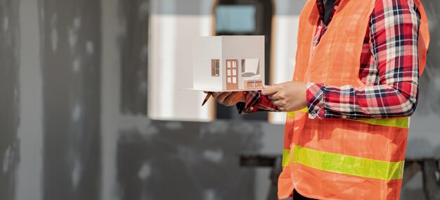 Mulher de engenharia e arquiteto trabalhando com modelo de casa no canteiro de obras.