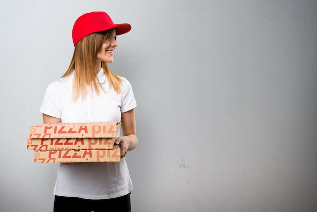 Mulher de entrega de pizza olhando lateral no plano de fundo texturizado