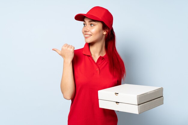 Mulher de entrega de pizza segurando uma pizza apontando para o lado para apresentar um produto