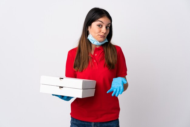 Mulher de entrega de pizza segurando uma pizza isolada no branco fazendo dúvidas gesto enquanto levanta os ombros