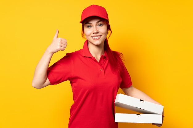 Mulher de entrega de pizza segurando uma pizza sobre parede isolada, dando um polegar para cima gesto