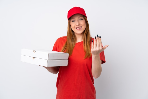 Mulher de entrega de pizza segurando uma pizza sobre parede rosa isolada, convidando para vir com a mão. Feliz que você veio