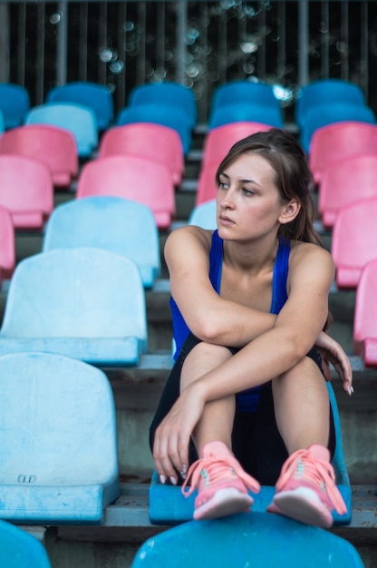 Mulher de esporte fitness em moda sportswear, senta-se olhando para a mulher de esporte em execução, exercício de fitness no estádio. conceito de estilo de vida saudável.