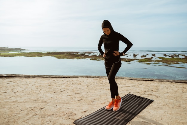 Mulher de esporte muçulmano na praia exercitando