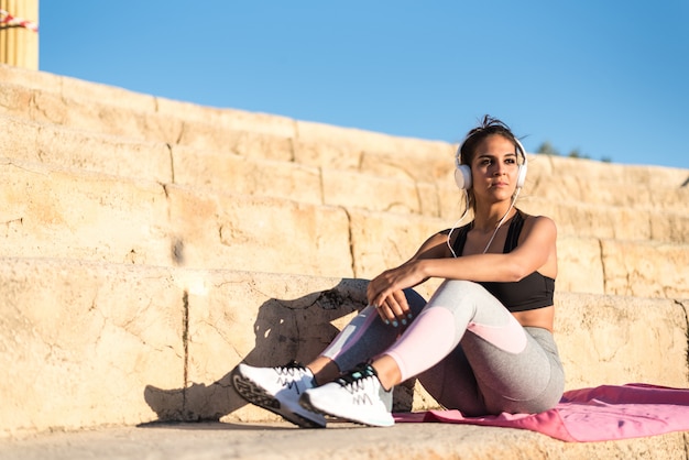 Mulher de esportes ao ar livre em uma escada descansando depois de fazer música exercício