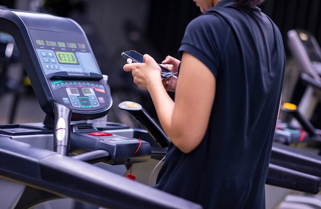 Mulher de esportes com um telefone na esteira