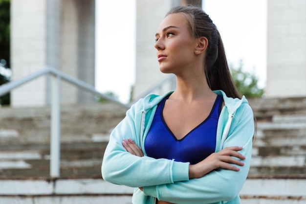 Mulher de esportes jovem incrível ao ar livre olhando de lado.