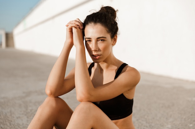 Mulher de esportes sentada no tapete ao ar livre na praia.