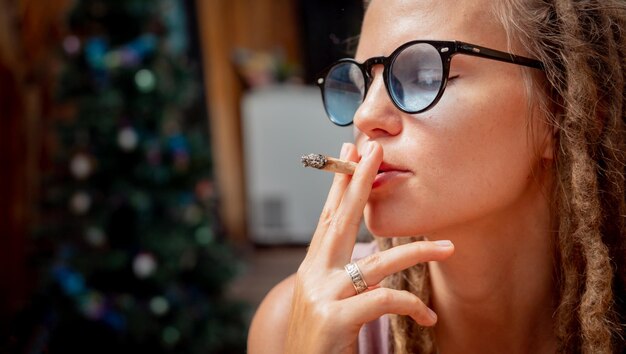 Mulher de estilo hippie fumando cigarros com maconha medicinal