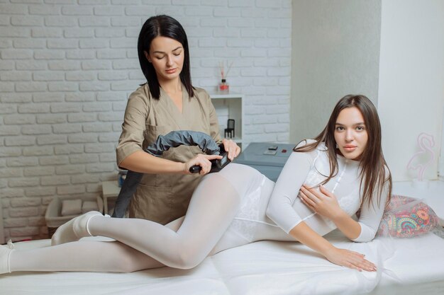 Foto mulher de fato branco especial recebendo massagem anti-celulite em um salão de spa lpg e contorno corporal