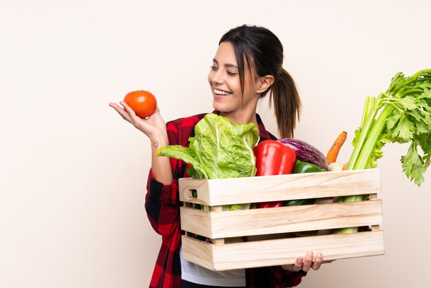 Mulher de fazendeiro segurando legumes frescos em uma cesta de madeira