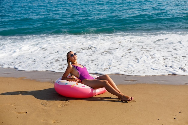 Mulher de férias na praia relaxando em um anel inflável na praia do oceano em viagens. menina em um maiô na praia na turquia