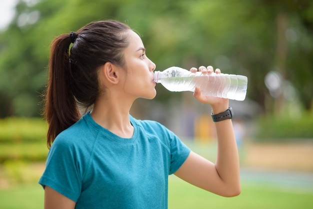 Mulher de fitness bebendo água após treino no parque